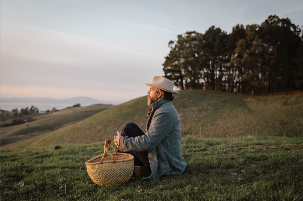 Day Schildkret sitting on a hillside at golden hour with a gathering basket